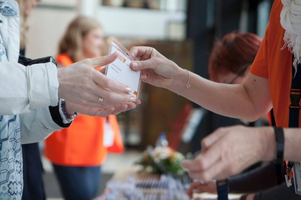 Person mottar sitt deltakerkort på Virak-konferansen 2017.